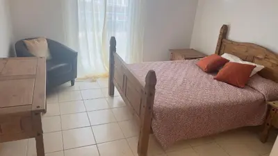 a bedroom with a wooden bed and a blue chair at Apartamento T2 equipado Vila Verde in Santa Maria