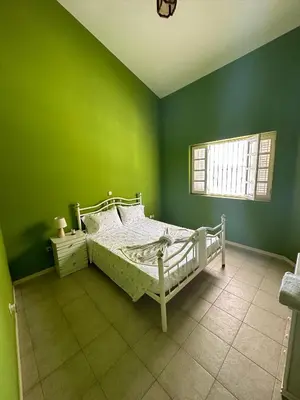 a green bedroom with a bed and a window at Djon’s place in Baia das Gatas