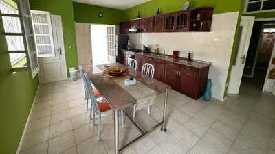 a kitchen with green walls and a table with chairs at Djon’s place in Baia das Gatas