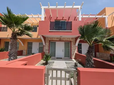 a red house with palm trees in front of it at Large Townhouse close to Beach in Sal Rei