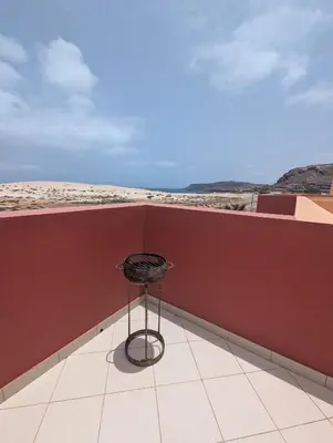 a black stool sitting on a balcony with a red wall at Large Townhouse close to Beach in Sal Rei