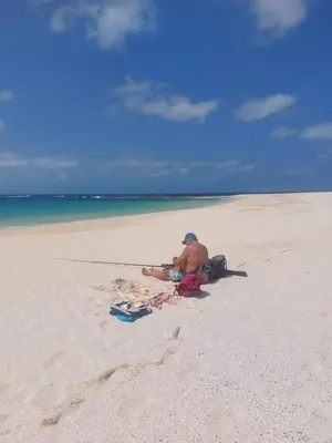 a man sitting on a beach next to the ocean at Vista Oceano - Boa Vista Island in Sal Rei