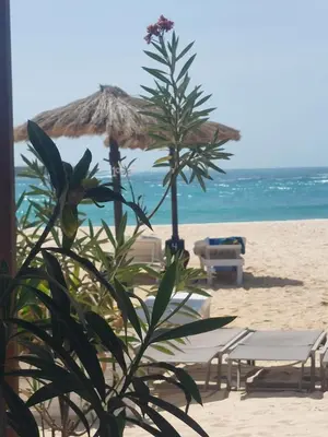 a beach with two chairs and an umbrella on the sand at Vista Oceano - Boa Vista Island in Sal Rei