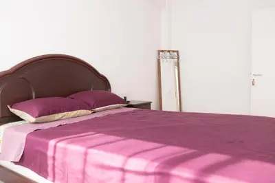 a bed with a purple blanket and pillows on it at 3 bdr cozy apt in Condominio Mi, Palmarejo Grande in Praia