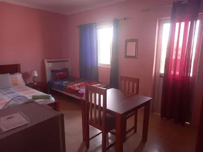 a bedroom with a table and a bed and a window at Casa Barreto in Tarrafal