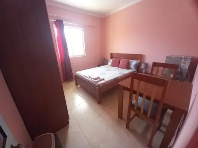 a bedroom with a bed and a table and a window at Casa Barreto in Tarrafal