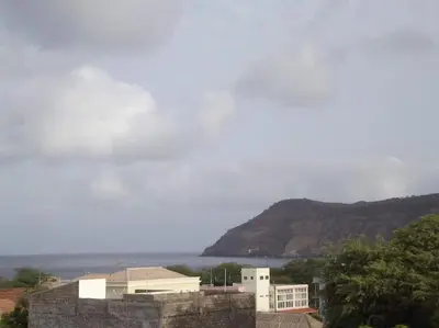 a view of the ocean and a building with a mountain at Maison familiale à Tarrafal. in Tarrafal