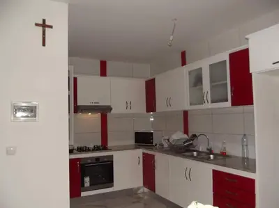 a kitchen with red and white cabinets and a cross on the wall at Maison familiale à Tarrafal. in Tarrafal