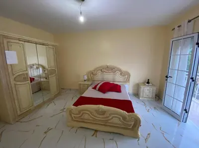 a bedroom with a large bed with red and white sheets at Maison familiale à Tarrafal. in Tarrafal