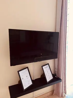 a flat screen tv on a shelf with two tablet screens at Good Dreams Apartment in Praia