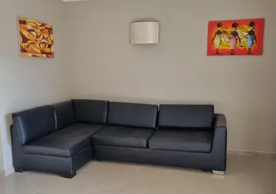 a black leather couch in a room with two paintings at Isla de Sal in Santa Maria