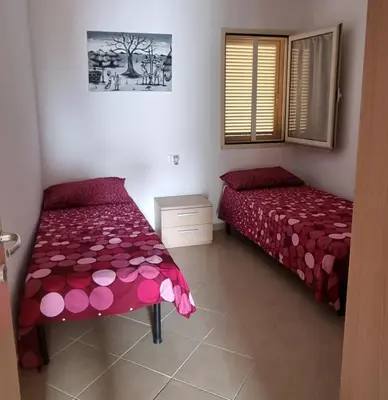 a bedroom with two beds with red and pink sheets at Isla de Sal in Santa Maria