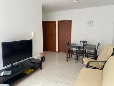 a living room with a flat screen tv and a table at Apartamento Santos in Ribeira Grande
