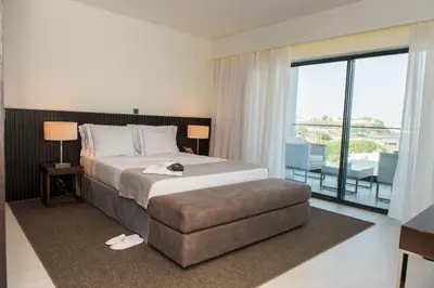 a hotel room with a large bed and a balcony at Hotel Pérola in Praia