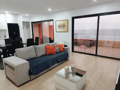 a living room with a blue couch and a table at Ocean Mirror Apartment in Praia