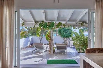 a patio with two chairs and a palm tree at Beach Villa - By Bobbywashere in Santa Maria