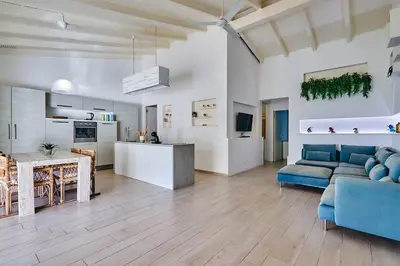 a living room with a blue couch and a kitchen at Beach Villa - By Bobbywashere in Santa Maria