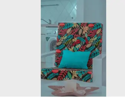 a colorful chair with a pillow and a washing machine at Vila na Mágica Baía da Murdeira in Beirona