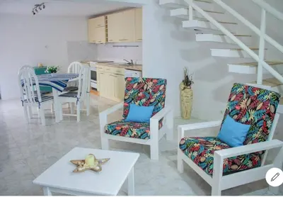 a living room with chairs and a table and a staircase at Vila na Mágica Baía da Murdeira in Beirona