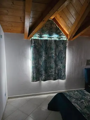 a bedroom with a curtain on the wall at Soleil Beach House in Santa Maria