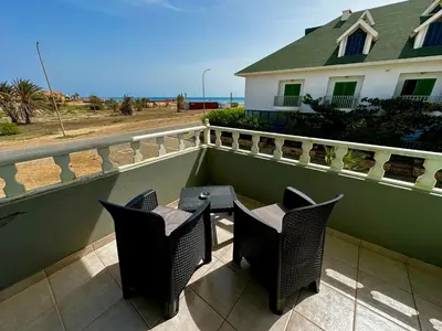 a patio with two chairs and a table on a balcony at Wind Holiday Apartments - By Bobbywashere in Santa Maria