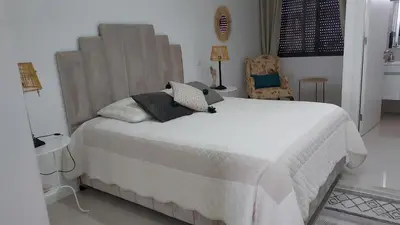 a bedroom with a large white bed and a chair at chambre chez alcinda in Mindelo