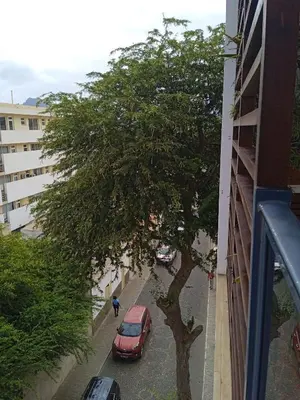 a red car parked next to a tree on a street at chambre chez alcinda in Mindelo