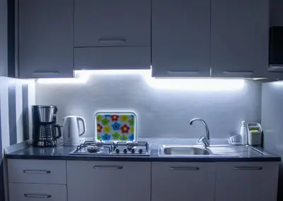 a kitchen with white cabinets and a sink with a light at Porto Antigo 2 - Apt 54 in Santa Maria
