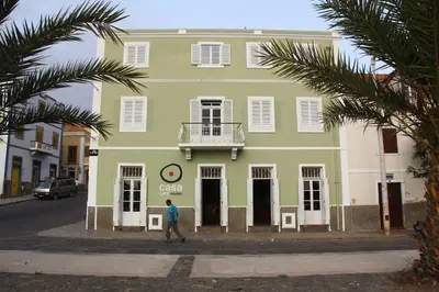 a person walking in front of a green building at Casa Café Mindelo in Mindelo