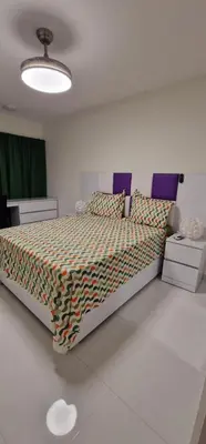 a bedroom with a bed with a comforter on it at SUITES-HOME, CIDADELA in Praia