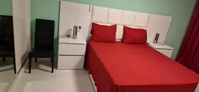 a bedroom with a red bed and a black chair at SUITES-HOME, CIDADELA in Praia