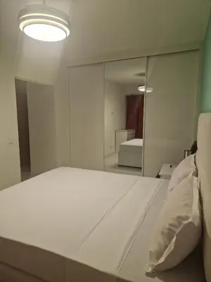 a bedroom with a white bed and a mirror at SUITES-HOME, CIDADELA in Praia