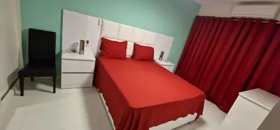 a bedroom with a red bed and a red curtain at SUITES-HOME, CIDADELA in Praia