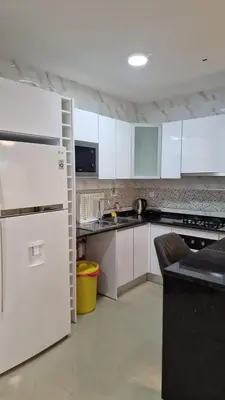 a kitchen with white cabinets and a white refrigerator at SUITES-HOME, CIDADELA in Praia