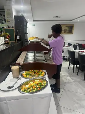 a woman preparing food in a kitchen with plates of food at Residencial Santo Amaro in Tarrafal