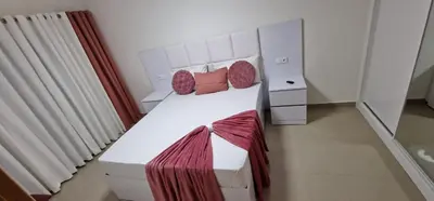 a small bedroom with a white bed with red sheets at SUITES-HOME, CIDADELA in Praia