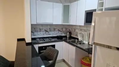 a kitchen with white cabinets and a sink and a stove at SUITES-HOME, CIDADELA in Praia
