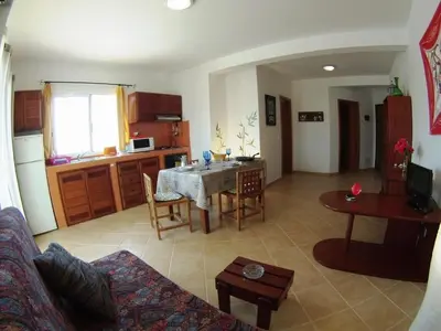 a living room with a table and a kitchen at Casa Bahia 5 in Santa Maria