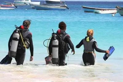 a group of three people walking into the ocean at Casa Bahia 8 in Santa Maria