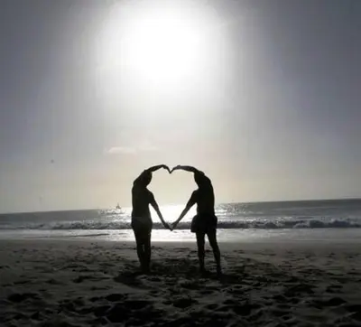 two people standing on the beach forming a heart at Casa Bahia 10 Grande Penthouse in Santa Maria
