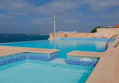 a large swimming pool with blue water and the ocean at Appartamento BICA. Stella Maris Exclusive in Calheta Do Maio