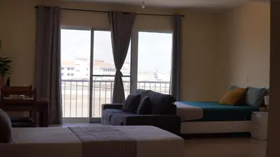 a room with two beds and a couch and a window at Beauty Plaza Suites in Santa Maria