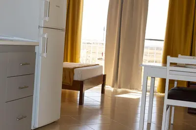 a kitchen with a refrigerator and a desk and a window at Beauty Plaza Suites in Santa Maria