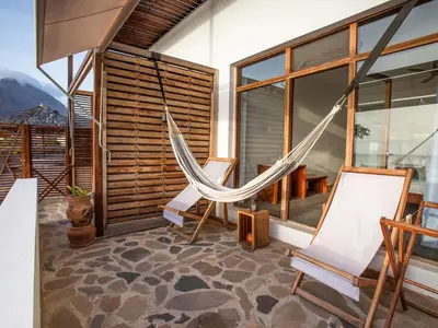 a room with a hammock and chairs on a balcony at King Fisher Village Eco-Boutique Hotel in Tarrafal