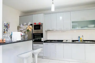 a white kitchen with white cabinets and appliances at Nhu Sao Francisco - PALMAREJO T3 in Praia