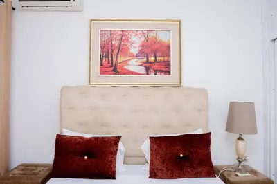a bed with two pillows and a painting on the wall at Nhu Sao Francisco - PALMAREJO T3 in Praia