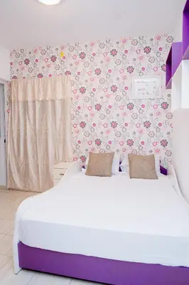a bedroom with a white bed with flowers on the wall at Nhu Sao Francisco - PALMAREJO T3 in Praia