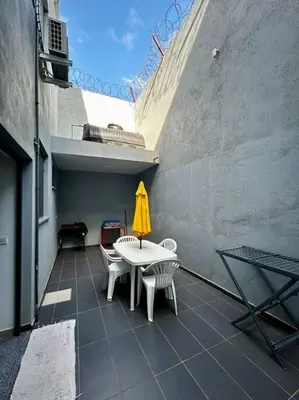 a patio with a table and chairs and a yellow umbrella at Modern Apartment in Praia Baixo - 1 min Walking to Beach in Praia Baixo