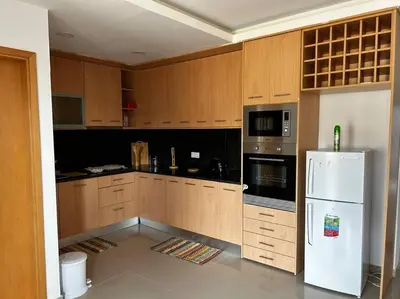 a kitchen with wooden cabinets and a white refrigerator at Modern Apartment in Praia Baixo - 1 min Walking to Beach in Praia Baixo