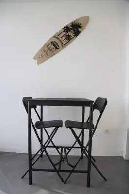 a table with a chair and a surfboard on a wall at Maison da Praia in Praia